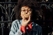 © TrueShot | Westend61 - Close-up of young woman with curly hair eating donut against fence in city