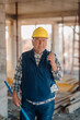 © Ljustina - Senior construction worker using walkie-talkie and holding spirit level on site