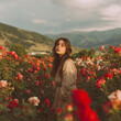 © heerim studio - Young woman in a beautiful rose field, mountains in the background, lost in a dream, soft sunlight.