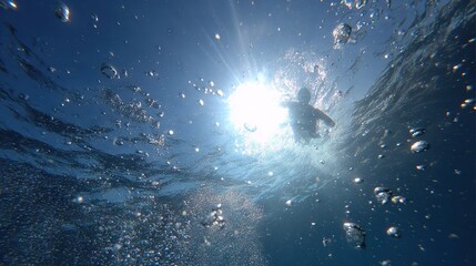 Wall Mural - a person swimming in the clear blue sea under a warm golden sun with sparkling bubble trails beneath