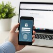 © Salma - Person holding smartphone with biometric fingerprint login screen in front of laptop