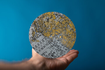 Poster - Hand holding a globe with a city map, representing urban development and planning.