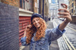 © Marko Geber - Smiling tourist woman taking selfie on rainy day in European city street