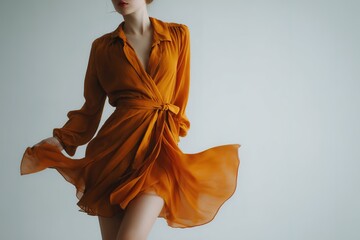 Poster - Woman in flowing orange dress twirls gracefully in a minimalist studio setting during a bright afternoon