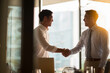 © Olivia - Asian Businessman making handshake with partner, open office space background