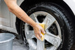 © Tosh Lubek - Man's arm with soapy yellow sponge cleaning alloy wheel