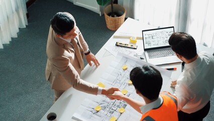 Poster - Top view of professional architect engineer team inspect house model while manager holding blueprint and asking about building construction. Group of diverse engineer working together. Alimentation.