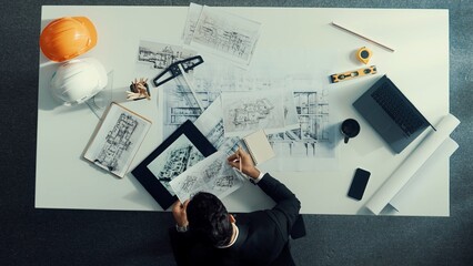 Poster - Top down view of civil engineer planning construction and looking at blueprint while sitting at meeting table with project plan, laptop. Architect taking a note about building design. Alimentation.