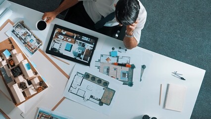 Poster - Top view of engineer drink coffee and thinking about house plan at meeting table with equipment and safety helmet scatter around. Aerial view of stressful manager looking at blueprint. Alimentation.