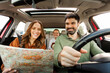 © Home-stock - Auto tourism concept. Happy European family sitting in car looking at road map for planning trip, parents and daughter choosing destination traveling together