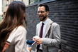 © Zoran Jesic - Businessman laughing with colleague holding coffee and tablet in the city