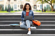 © Prostock-studio - Joyful young indian woman student studying online, using laptop computer outdoors, sitting on stairs at college campus, doing homework, copy space. E-learning concept
