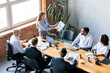 © Prostock-studio - Corporate Meeting. Business Lady Showing Charts To Coworkers Analyzing Company Growth Sitting On Table In Modern Office