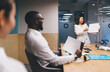© BullRun - Young Asian woman in blazer confidently holding presentation papers in front of diverse coworkers in a high-tech conference room, highlighting digital literacy and visual storytelling in business