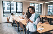 © BullRun - Confident young Caucasian businesswoman using smartphone for work tasks while standing in open office space, focused on mobile communication, digital productivity, or online research