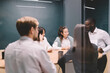 © BullRun - Diverse team having brainstorming session in glass meeting room, discussing ideas and digital tools around table, focused on collaborative tech project in startup workspace