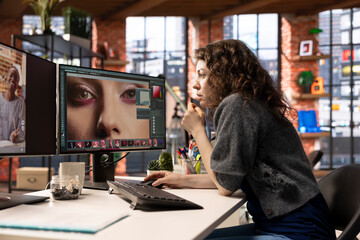 Poster - Female editor designer retouches photos on dual monitors desktop, computer setup in a creative office. Ideal workspace for digital media professional focused on photo editing.