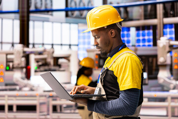 Poster - Male engineer with laptop inspects smart manufacturing machinery, ensuring automated factory operations. African American technician uses digital interface for optimization of industry 4.0 system.