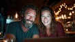 © Dulemegapixel - A cheerful couple shares a joyful moment together while using a laptop, surrounded by warm ambient lighting, showcasing the essence of companionship and connection at home.