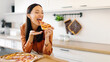 © Home-stock - Excited young woman eating pizza, biting slice and enjoying its smell and taste, being satisfied with fast food delivery service. Lunch time at home