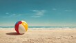 © Kasim - Beach ball rests on sandy shore, ocean waves in background; summer vacation concept