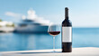 © Myroslava - Bottle of red wine with white mockup label and a glass of wine on a wooden deck with a luxury yacht and ocean in the background