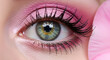 © Lunatic - A captivating close-up of a beautiful eye with bright pink eyeshadow. The eye is filled with sparkling green hues and long, dark lashes. A pink petal delicately adorns the image.