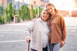 © Pixel-Shot - Senior woman with stick and caregiver hugging outdoors