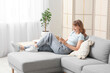 © Pixel-Shot - Beautiful young woman using mobile phone on grey sofa at home