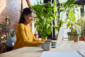 Smiling businesswoman surfing net through laptop at loft office