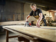 © BusinessClass by W61 - Carpenter cutting oriented strand board with circular saw in workshop