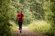 © Cavan Images - Young caucasian man running through green summer forest park.