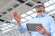 © BusinessClass by W61 - Businessman wearing virtual reality simulator gesturing and holding tablet PC at industry