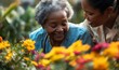 © Riya Kanu - Happy elderly Black African American woman in a wheelchair smelling flowers in a hospice nursing care home garden. African American pensioner with nurse, Generative AI