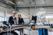 © BusinessClass by W61 - Businessman and colleague standing near machine in factory