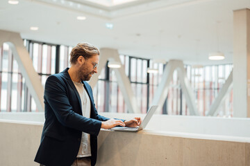 Businessman working with laptop on wall