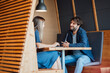 © BusinessClass by W61 - Smiling business people sitting with laptop and talking in office cubicle