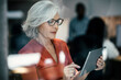 © BusinessClass by W61 - Senior businesswoman using tablet PC seen through glass window