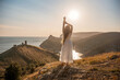 © svetograph - woman stands on a hill overlooking the ocean, her arms raised in the air. Concept of freedom and joy, as if the woman is celebrating a moment of happiness or accomplishment.