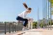 © Maria Vitkovska - Young woman performing jump squats outdoors in urban environment