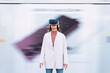 © BusinessClass by W61 - Businesswoman wearing virtual reality simulator standing in front of wall