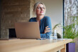© BusinessClass by W61 - Blond woman wearing eyeglasses sitting with laptop at table