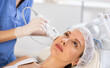 © JackF - Young woman cosmetologist performs facial whitening procedure with machine to young female client