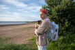 © DimaBerlin - Responsible kind man stroking scared cat companion at river shore, wear pet carrier backpack for comfortable journey. Seaside vacation with domestic animal, tourism with pets, human animal bond