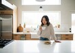 © Tida - Woman Enjoying Coffee and Cookies in Modern Kitchen - A young Asian woman stands in a bright, modern kitchen, enjoying a cup of coffee and some cookies.