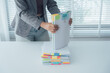 © Kritdanai - Stack of Organized Papers: A person carefully organizes a stack of documents with colored tabs, showcasing attention to detail and the value of structured information.
