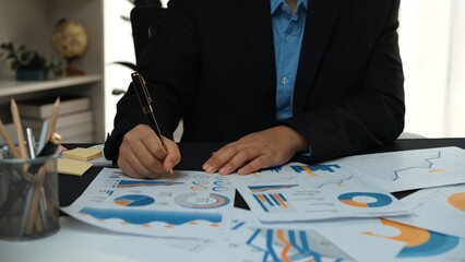 Poster - A professional individual conducts a detailed analysis of various business charts and graphs, demonstrating focus and engagement in a well-organized office setting.Noogenesis