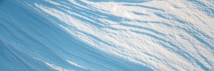 Wall Mural - Beautiful winter background with snowy ground. Natural snow texture. Wind sculpted patterns on snow surface. Wide panoramic texture for background and design.