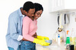 © Prostock-studio - Happy black guy hugging his cheerful girlfriend washing dishes, side view, panorama with copy space. Loving african american guy embracing his wife while she doing house work, washing dishes
