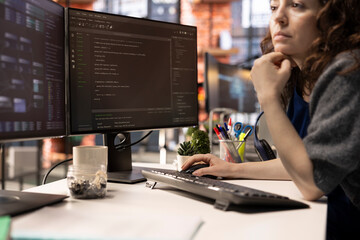 Poster - Female programmer seen typing code for a user interface design on dual monitors, working in a digital workspace. Woman IT specialist working on software engineering and front end development.